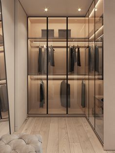 a walk - in closet with glass doors and lots of clothes on hangers next to a bench