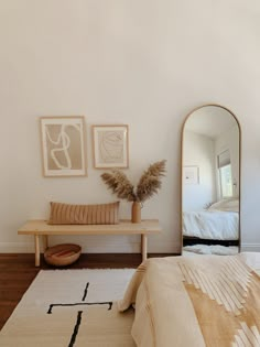 a bed room with a neatly made bed and a mirror on the wall above it