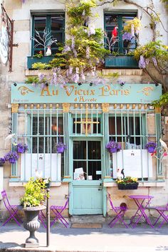 an image of a store front with flowers on the window sill and shutters