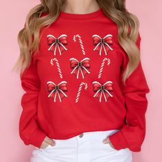 This Santa Bow Candy Cane Aesthetic Christmas Sweatshirt is perfect for cozy winter days, adding a festive and fun holiday style to your wardrobe. Great as a gift for women, this cute pullover captures the joyful spirit of the season with a charming aesthetic. 𝐃𝐄𝐓𝐀𝐈𝐋𝐒 Gildan 18000 Sweatshirt ❄️ 50% cotton, 50% polyester ❄️ Medium-heavy fabric (8.0 oz/yd² (271.25 g/m²) ❄️ Loose fit ❄️ Sewn-in label ❄️ Runs true to size Gildan 2400 Long Sleeve Tee ❄️ 100% cotton (fiber content may vary for different colors) ❄️ Medium fabric (6.0 oz/yd² (203 g/m ❄️ Classic fit ❄️ Sewn-in label ❄️ Runs smaller than usual for men; very loose fit for women Gildan 64000 Short Sleeve T-Shirt ❄️ 100% cotton (fiber content may vary for different colors) ❄️ Lightweight fabric (4.5 oz/yd² (153 g/m ❄️ Classic fi Festive Long Sleeve Cotton Sweater, Cozy Crew Neck Top For Holidays, Red Winter Sweatshirt As Gift, Cute Winter Sweater As A Gift, Festive Long Sleeve Fall Sweatshirt, Cute Winter Holiday Tops, Red Long Sleeve Top For Gifts, Casual Christmas Sweatshirt For Festive Occasion, Casual Christmas Sweatshirt