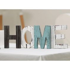 the word home spelled with wooden letters on a table in front of a white wall