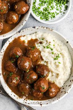 two bowls filled with mashed potatoes, meatballs and gravy on a table