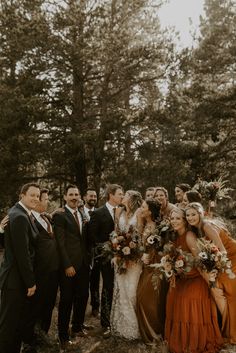 a group of people standing next to each other in front of some tall trees and grass