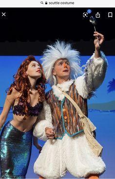 two people dressed in costumes on stage with one holding a wand and the other looking up