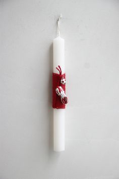 a white candle with a red scarf hanging from it's side on a wall