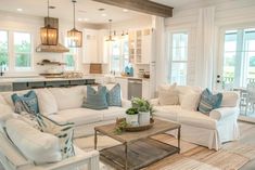 a living room filled with white furniture and lots of pillows on top of it's couches