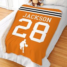 a bed with an orange jersey on it and a teddy bear sitting next to it