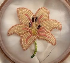 a beaded flower in a wooden frame