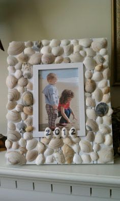 a photo frame made out of seashells on a mantle next to a fire hydrant