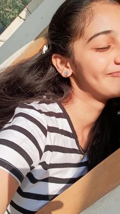 a woman holding a cell phone up to her ear while sitting on a bench outside