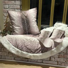 a hammock chair sitting in front of a brick wall with pillows on it