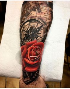 a man's arm with a red rose and compass tattoo on the left forearm