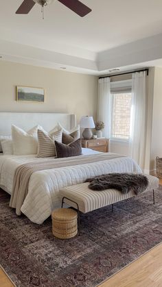 a bedroom with a bed, rug and ceiling fan in the middle of the room