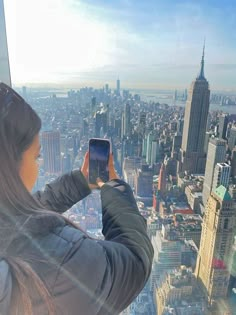 a woman taking a photo from the top of a building with her cell phone in new york city