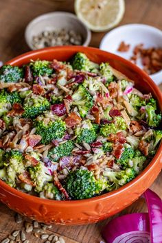 a bowl filled with broccoli and bacon on top of a wooden table