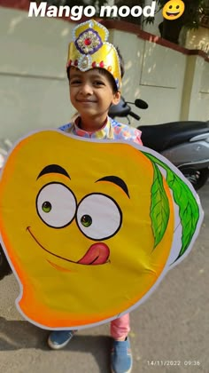 a young boy holding up a large yellow sign with an emoticive face on it