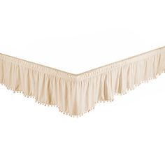 a white bed skirt with tassels on the bottom and an attached ruffled edge