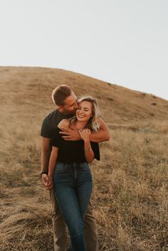 a man and woman hugging in the middle of a field