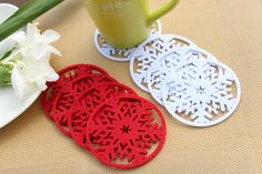 three red and white doily sitting on top of a table next to a vase