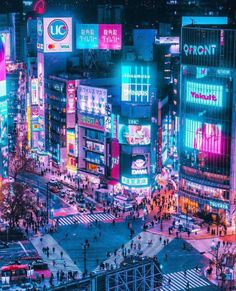 an aerial view of a city at night with neon lights and people crossing the street