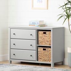 a grey dresser with three baskets on top and a potted plant next to it