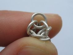 someone is holding a silver ring in their left hand and it looks like an intertwined knot