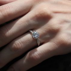 a woman's hand with a diamond ring on her left hand, showing the center stone