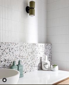 a white sink sitting under a faucet next to a wall mounted soap dispenser