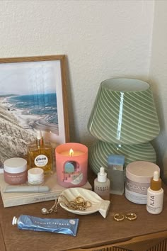 an assortment of personal care items on a table next to a framed photograph and lamp