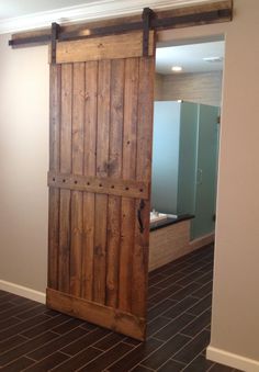 an open wooden door in the middle of a room with tile flooring and walls