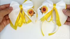 two white and yellow bows with sunflowers on the top one being held by someone's hand