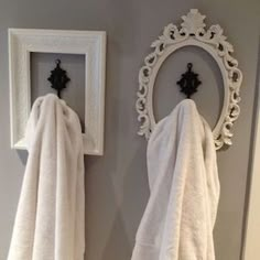 two white towels hanging on the wall next to a mirror