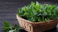 a basket filled with green leaves on top of a wooden table