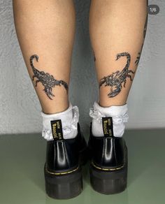 the legs and ankles of a person with tattoos on them, both wearing black rubber boots