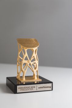 a wooden chair sitting on top of a black and white book holder with a gold finish