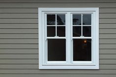 a white window sitting on the side of a gray house