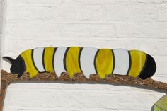 a yellow and black caterpillar sitting on top of a white brick wall