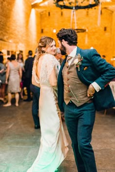 a bride and groom dance together at their wedding reception in an old brick building with chandeliers hanging from the ceiling