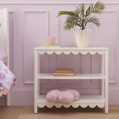 a small white shelf next to a bed