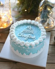 a blue and white frosted cake sitting on top of a table next to christmas decorations