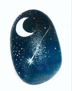 a painted rock with the moon and stars on it's side, against a white background