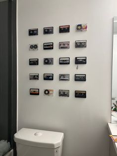 a white toilet sitting in a bathroom next to a wall with cassettes on it