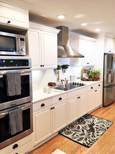 a kitchen with white cabinets, stainless steel appliances and wooden floors is pictured in this image