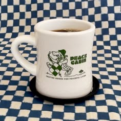 a coffee cup sitting on top of a blue and white checkered table cloth