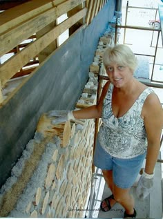 a woman standing in front of a stone wall with wood planks on the sides