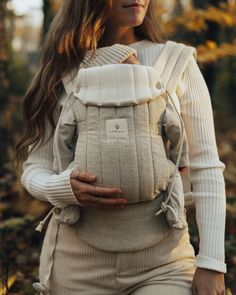 a woman is carrying a baby in a sling carrier, with her hands on her hips