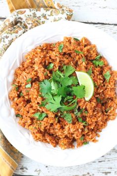 mexican rice with cilantro and lime in a white bowl on a wooden table