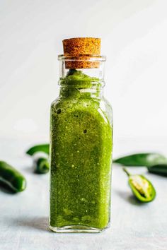 a green smoothie in a glass bottle with a cork top on a white surface