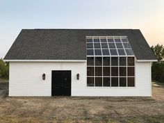 a white barn with a black door and windows