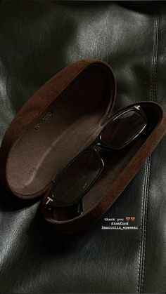 a pair of glasses sitting in a case on top of a black leather couch,